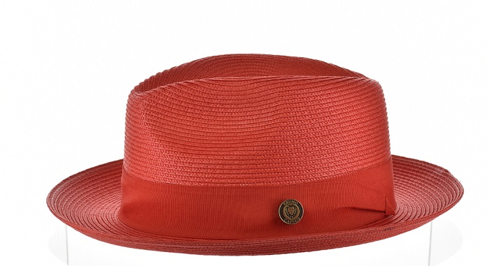Red straw fedora hat with a dark reddish-brown band and a small metal emblem.
